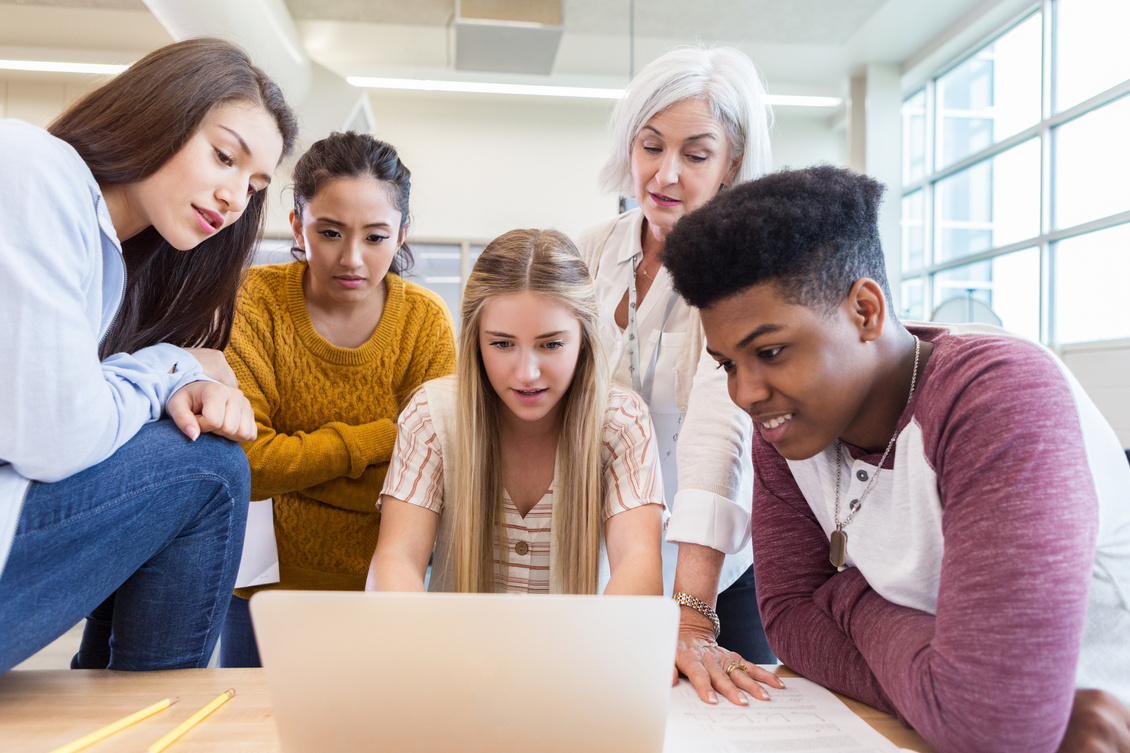 Group of high school students share laptop